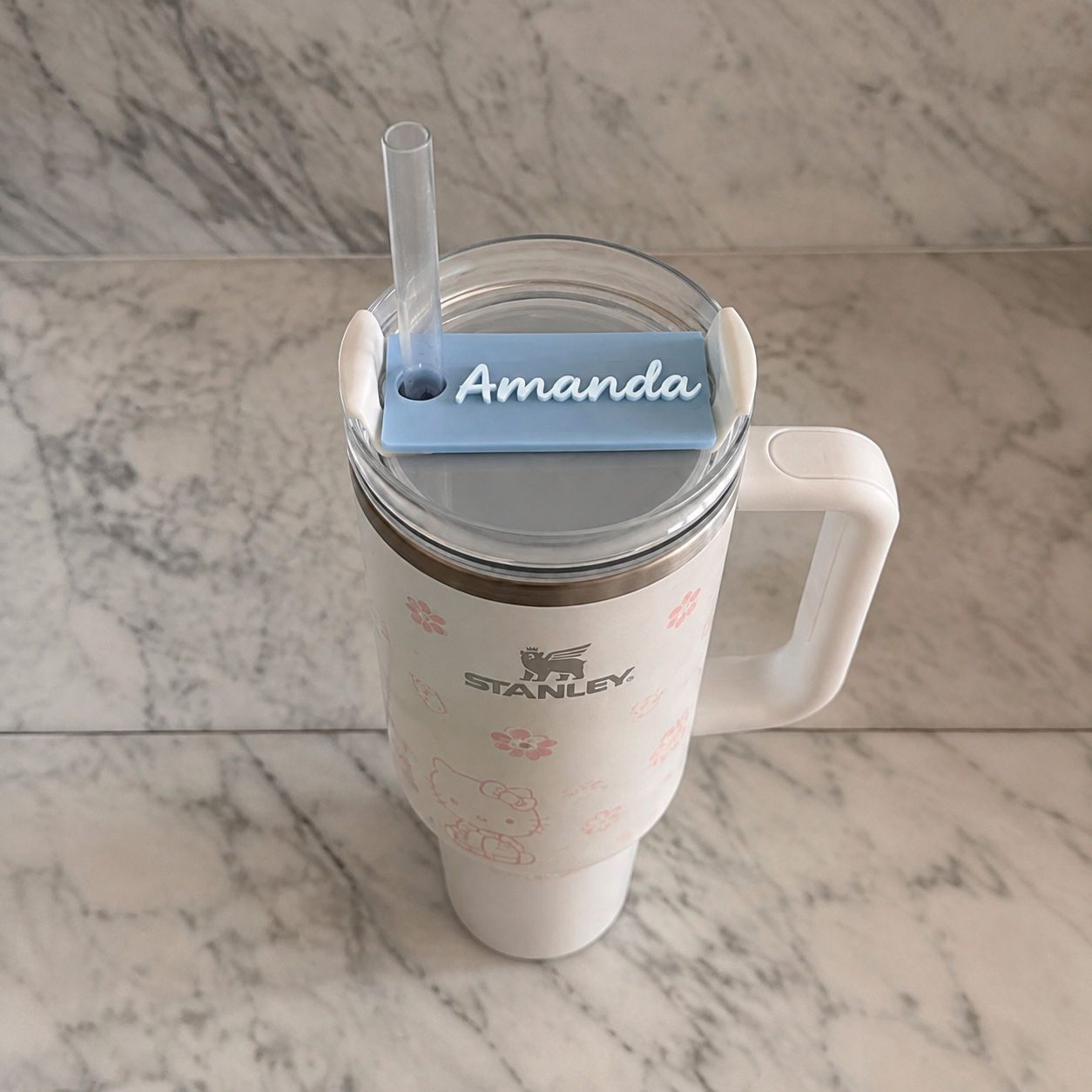 Blue personalized lid topper on tumbler in a marble setting