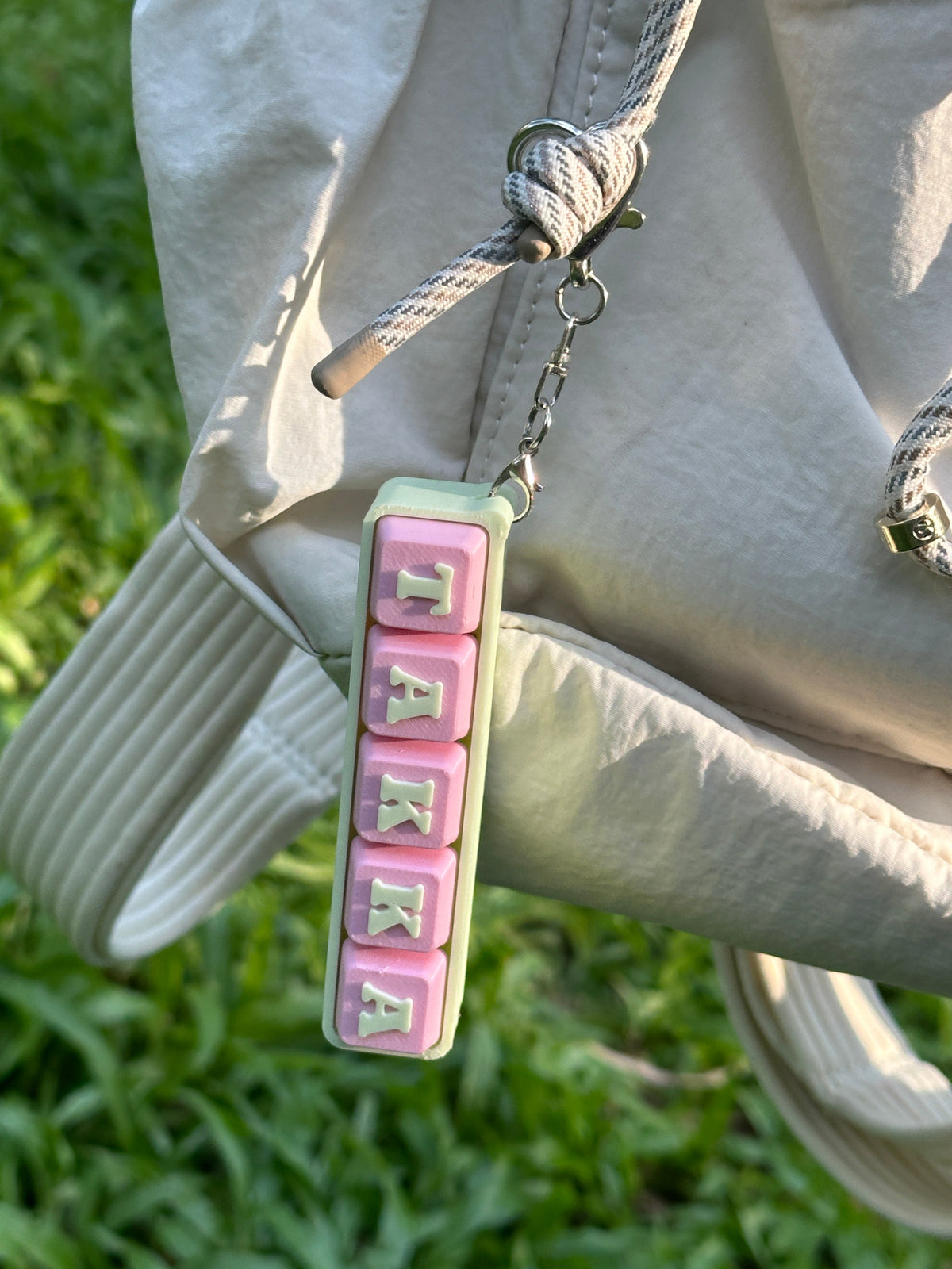Personalized TAKKA keyboard key toy hanging from a backpack
