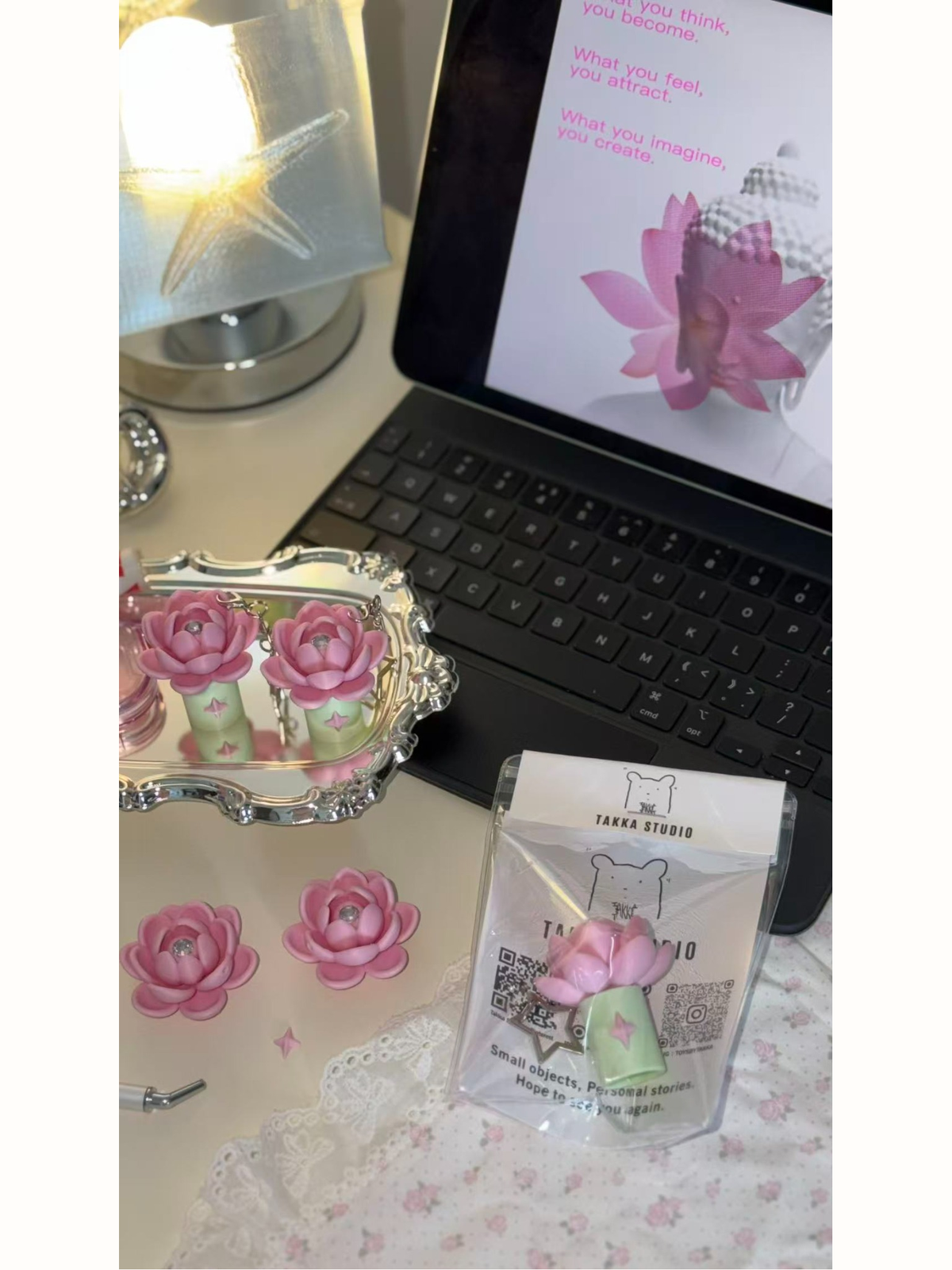 Pink lotus charm with Takka packaging in a studio setting
